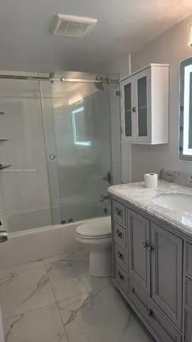 a bathroom with a granite countertop sink toilet and shower