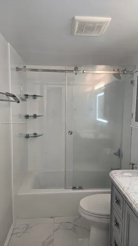 a bathroom with a granite countertop toilet a sink and shower