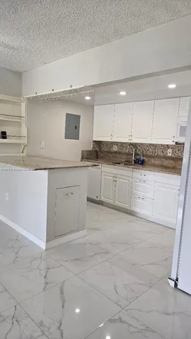 a large kitchen with granite countertop a sink and cabinets