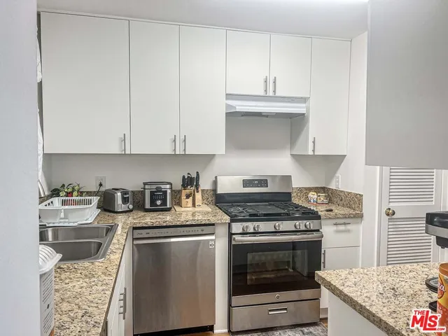 a kitchen with granite countertop a stove sink and cabinets