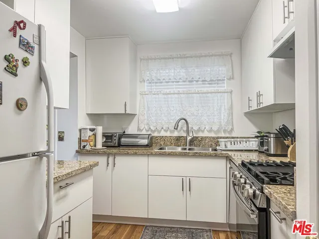 a kitchen with stainless steel appliances granite countertop a sink stove refrigerator and cabinets