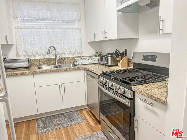 a kitchen with granite countertop a sink stove and cabinets