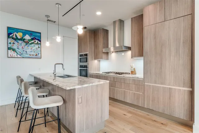 a kitchen with stainless steel appliances granite countertop a sink a stove a refrigerator and island with wooden floor