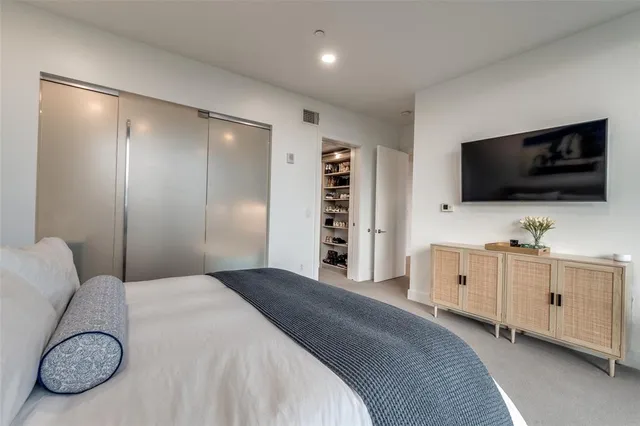 a spacious bedroom with a bed and a flat screen tv
