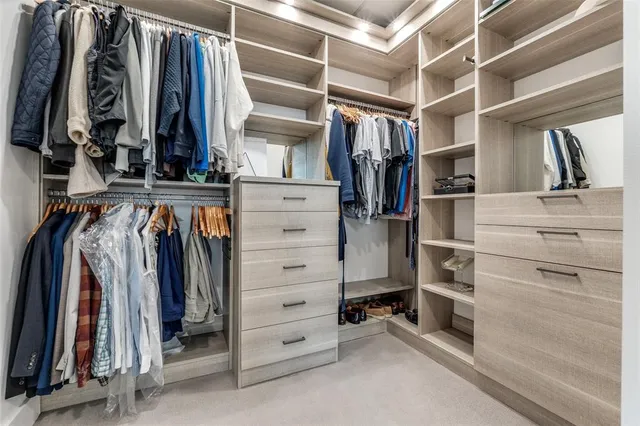 a view of walk in closet with clothes and shoes