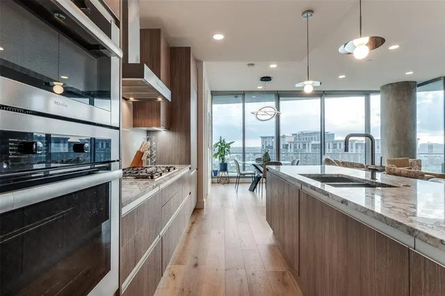 a large kitchen with stainless steel appliances a large counter top a stove a chimney a sink and a large window