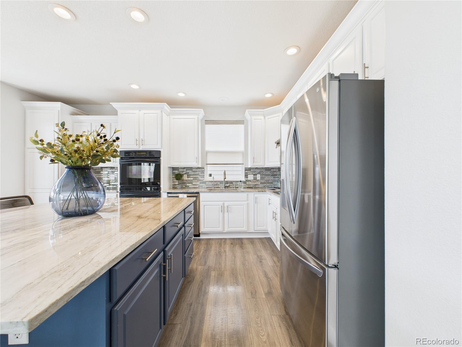 10501 Wagon Highlands Ranch Highlands Ranch, CO 80130 - Photo 12 of 50 a kitchen with kitchen island white cabinets and stainless steel appliances