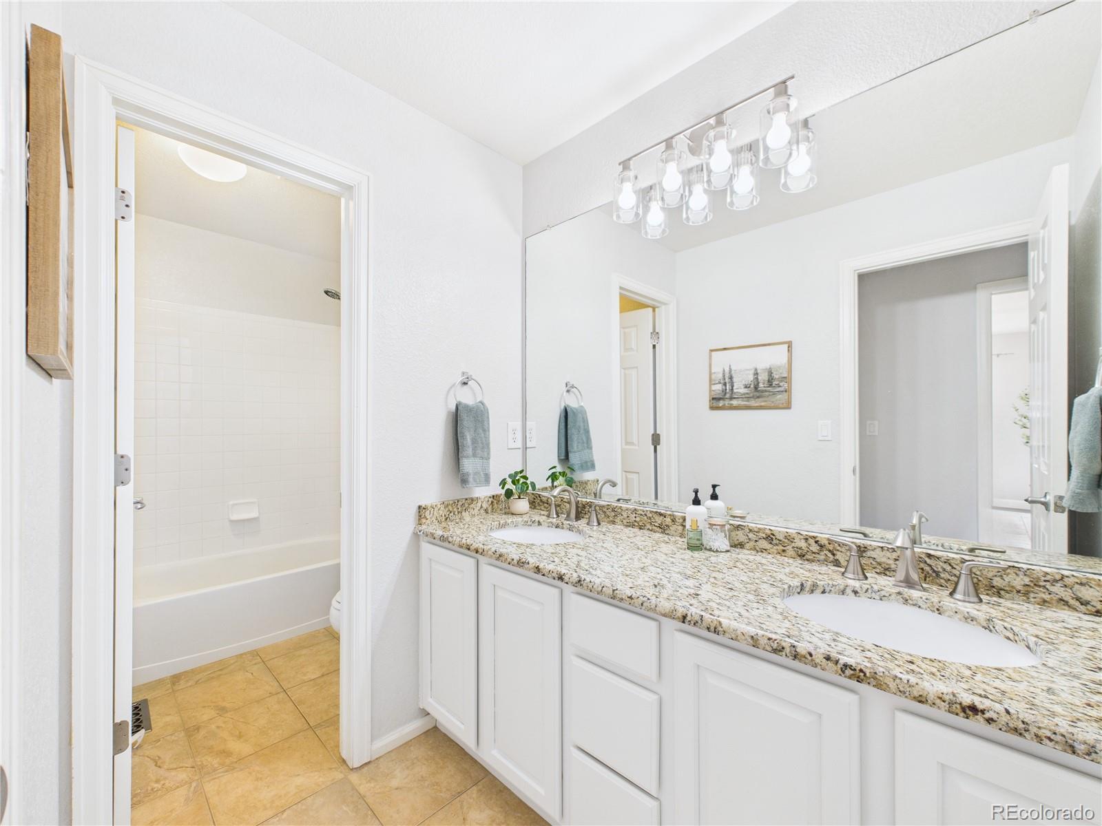 10501 Wagon Highlands Ranch Highlands Ranch, CO 80130 - Photo 20 of 50 a bathroom with a granite countertop sink a mirror and a bathtub