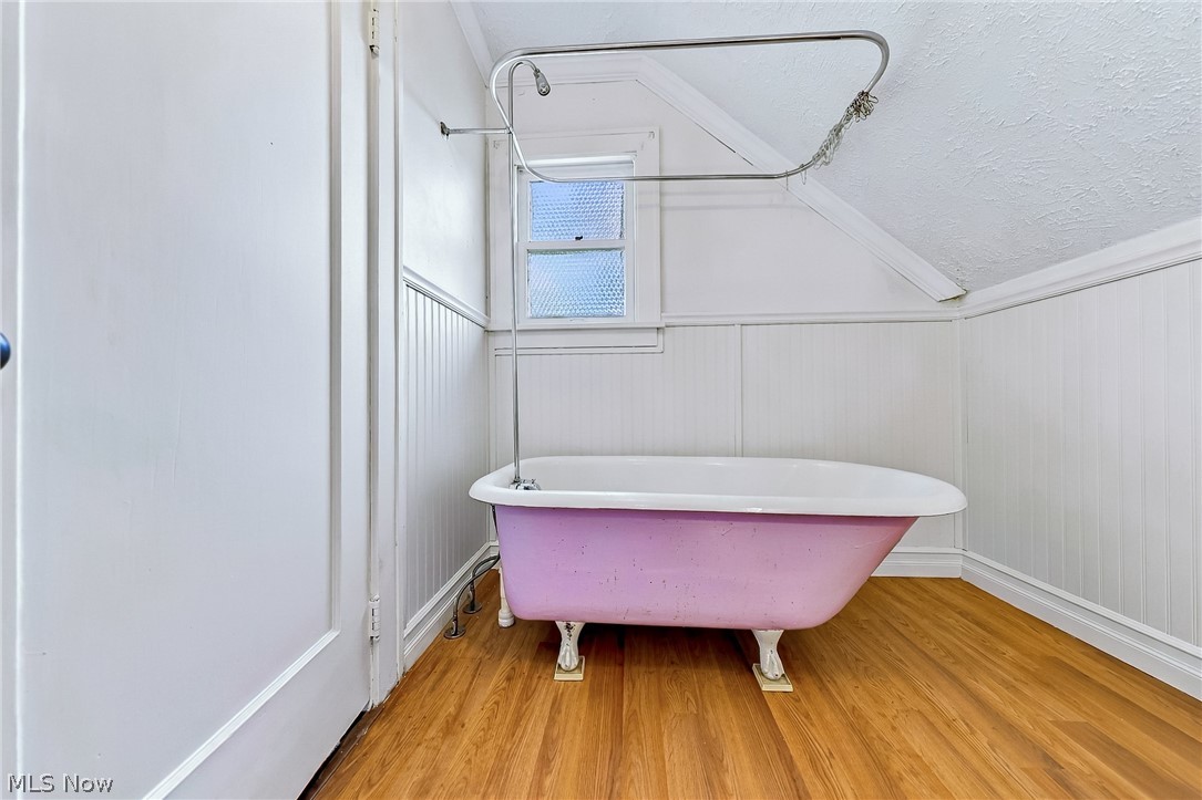 24958 Kennedy Ridge Road North Olmsted, OH 44070 - Photo 32 of 43 Freestanding clawfoot bathtub with shower curtain rod, wood-finish flooring, beadboard wall paneling, and an attic window