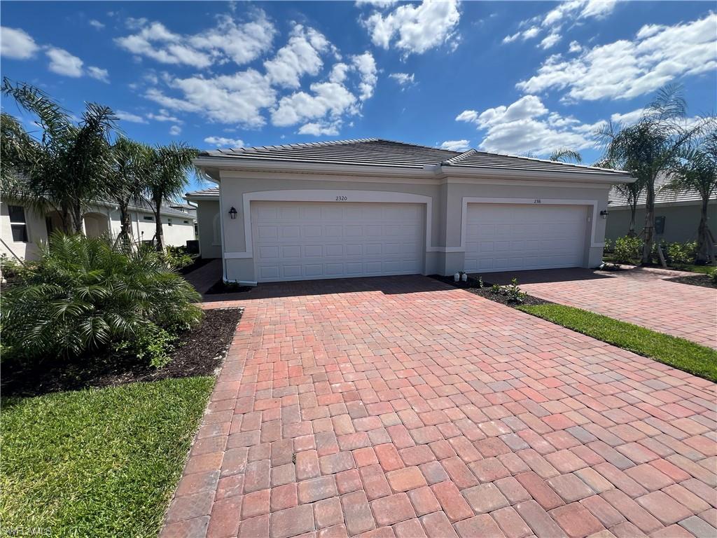 2320 Dragonfruit Way Naples, FL 34120 - Photo 2 of 33 View of front of house with a tiled roof, an attached garage, decorative driveway, and stucco siding