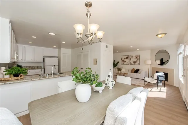 a dining room with wooden floor a chandelier a glass table and chairs