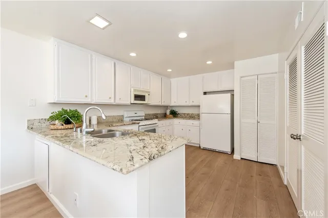 a kitchen with stainless steel appliances granite countertop a refrigerator sink and white cabinets