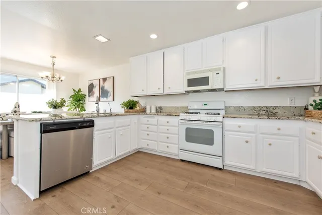 a kitchen with granite countertop white cabinets and white appliances