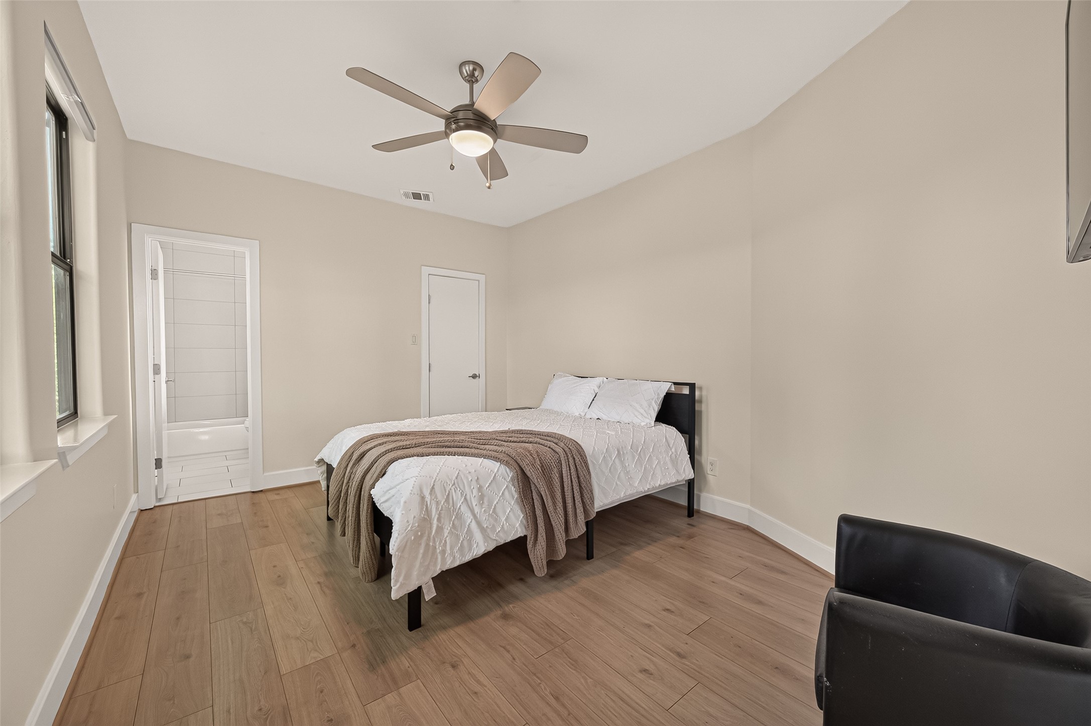 1767 Michigan Street Houston, TX 77006 - Photo 20 of 33 This secondary bedroom is bright and inviting, featuring a neutral color palette and wood flooring. There's an ensuite bathroom visible, adding convenience.