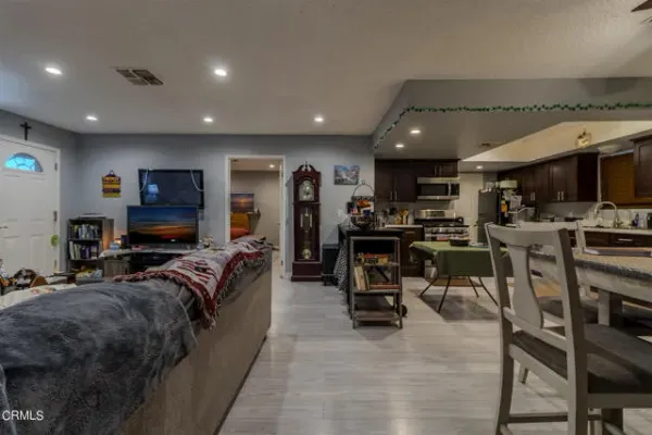 a kitchen with stainless steel appliances granite countertop a stove top oven a sink dishwasher a refrigerator and a dining table with wooden floor