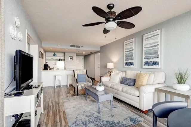 a living room with furniture a ceiling fan and a flat screen tv