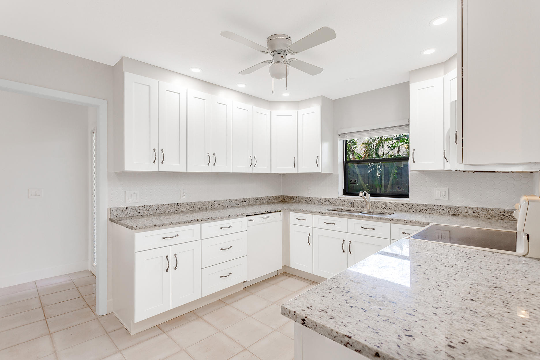 a kitchen with granite countertop a sink a stove and cabinets