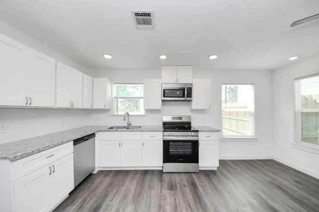a kitchen with granite countertop a sink stainless steel appliances and window