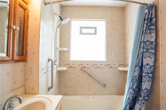 a bathroom with a bathtub a shower and a window