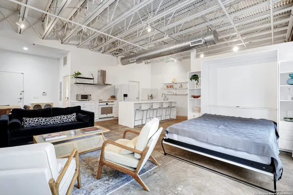 a bedroom with a bed couch and a view of living room