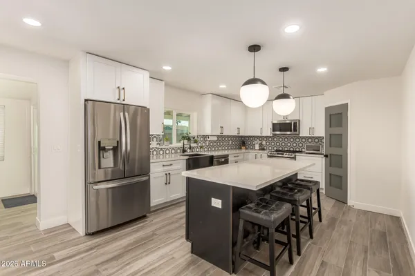 a kitchen with a stove a kitchen island and chairs in it