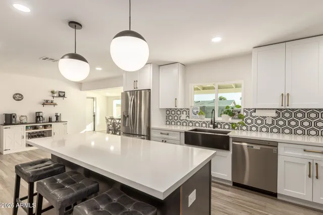 a kitchen with stainless steel appliances granite countertop a refrigerator a sink dishwasher a stove and white countertops with wooden floor