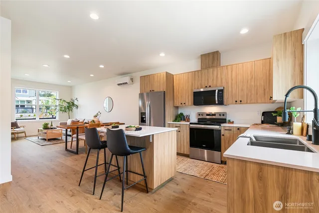 a kitchen with kitchen island granite countertop wooden cabinets a stove a sink a dining table and chairs