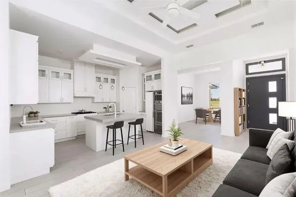 a living room with furniture a rug kitchen view and a table