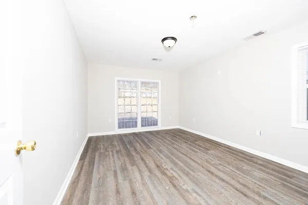 a view of an empty room with wooden floor and a window