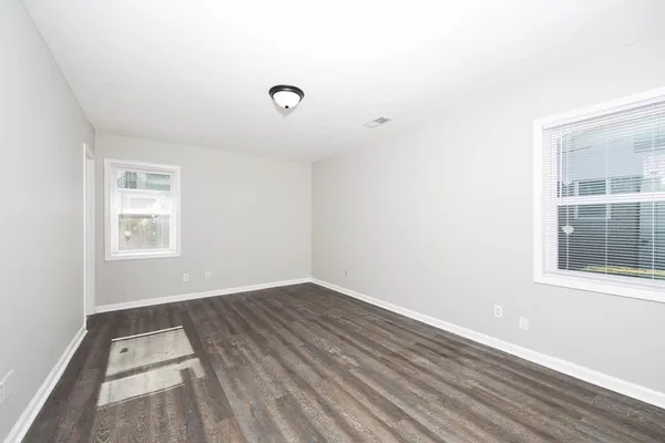 an empty room with wooden floor and windows