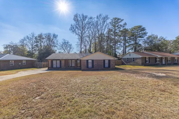 a view of a house with a yard and a large tree