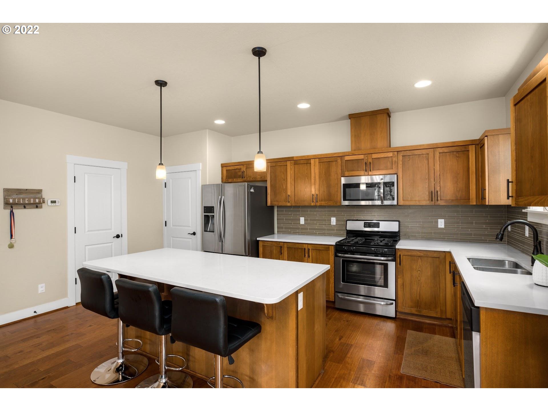 374 Southwest 202nd Terrace Beaverton, OR 97006 - Photo 11 of 28 a kitchen with stainless steel appliances kitchen island granite countertop a sink a stove a refrigerator cabinets and wooden floor