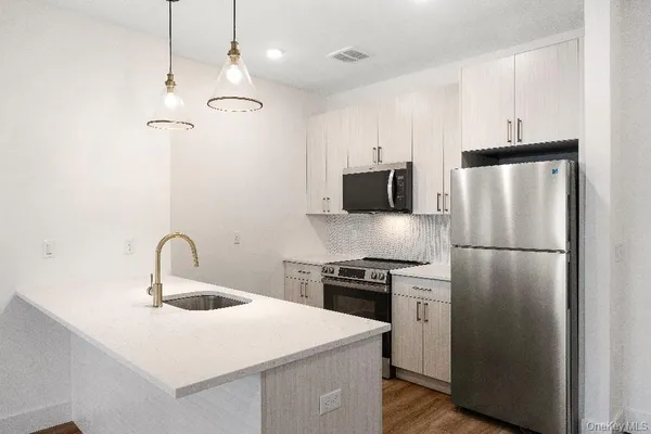 a kitchen with stainless steel appliances granite countertop a refrigerator a stove a sink a microwave and a refrigerator