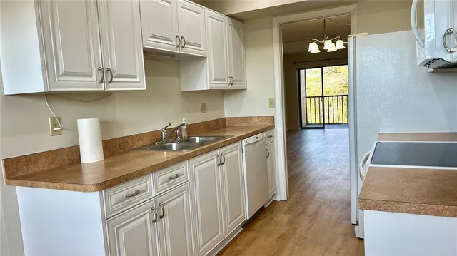 a kitchen with stainless steel appliances granite countertop a sink dishwasher and granite countertops with wooden floor