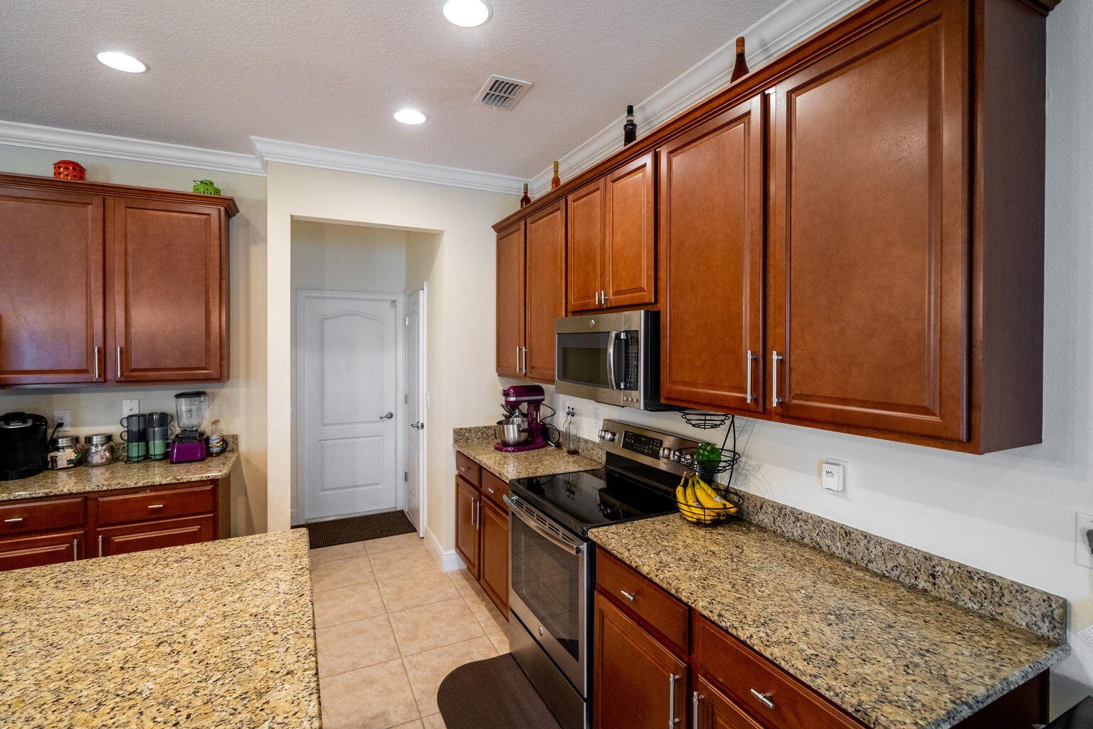 1026 Southwest Ingrassina Avenue Port St. Lucie, FL 34953 - Photo 7 of 20 a kitchen with stainless steel appliances granite countertop a stove sink and cabinets