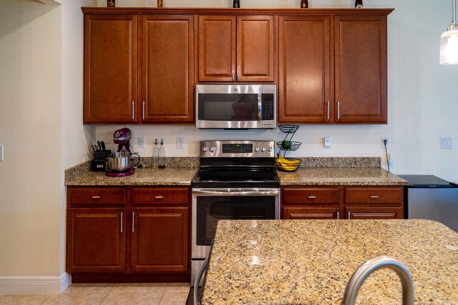 1026 Southwest Ingrassina Avenue Port St. Lucie, FL 34953 - Photo 8 of 20 a kitchen with granite countertop wood cabinets stainless steel appliances and a sink