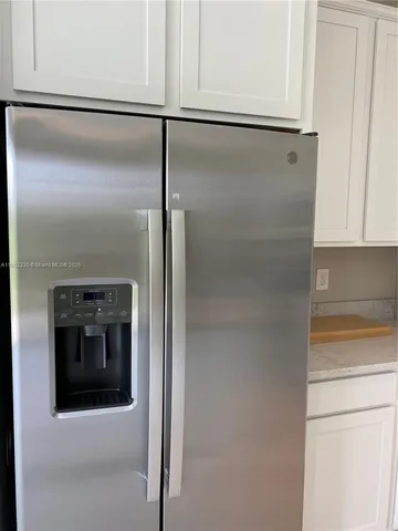 a view of a kitchen with white cabinets and stainless steel appliances
