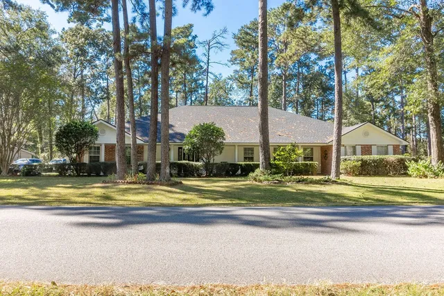 a view of a house with a big yard and large trees