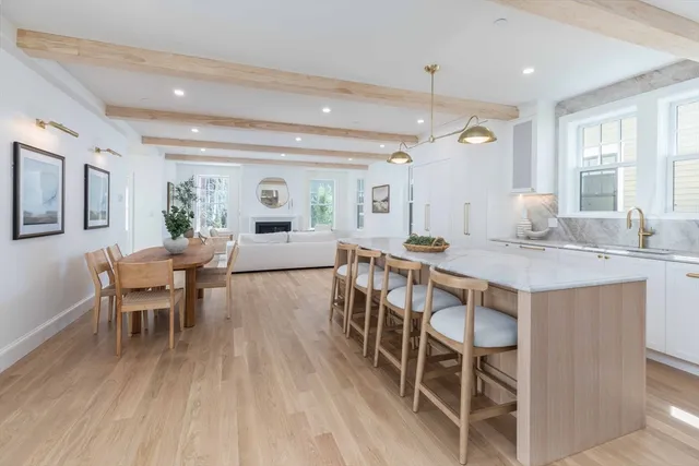 a dining hall with stainless steel appliances granite countertop a stove a sink a dining table and chairs with wooden floor