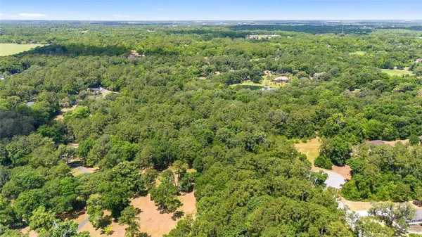 an aerial view of residential houses with outdoor space and trees
