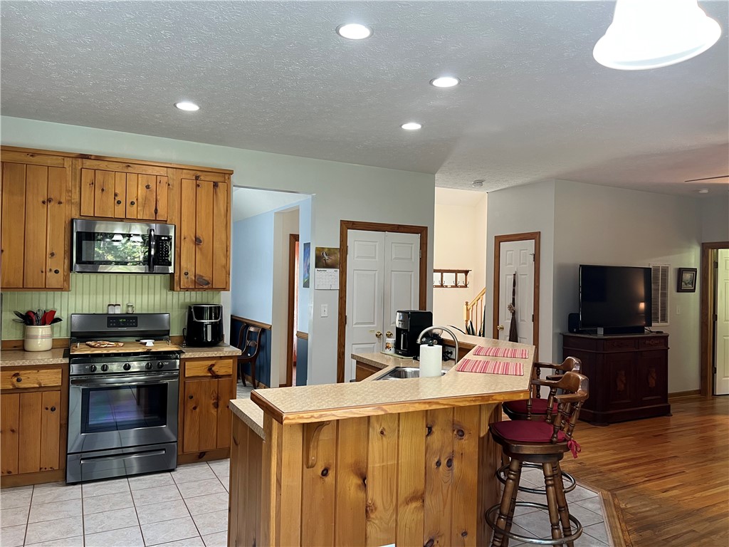 1419 Mill Creek Road Wake, VA 23176 - Photo 23 of 49 Kitchen featuring light countertops, appliances with stainless steel finishes, brown cabinetry, a kitchen bar, and a kitchen island with sink