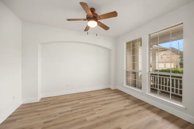 an empty room with a window and a fan