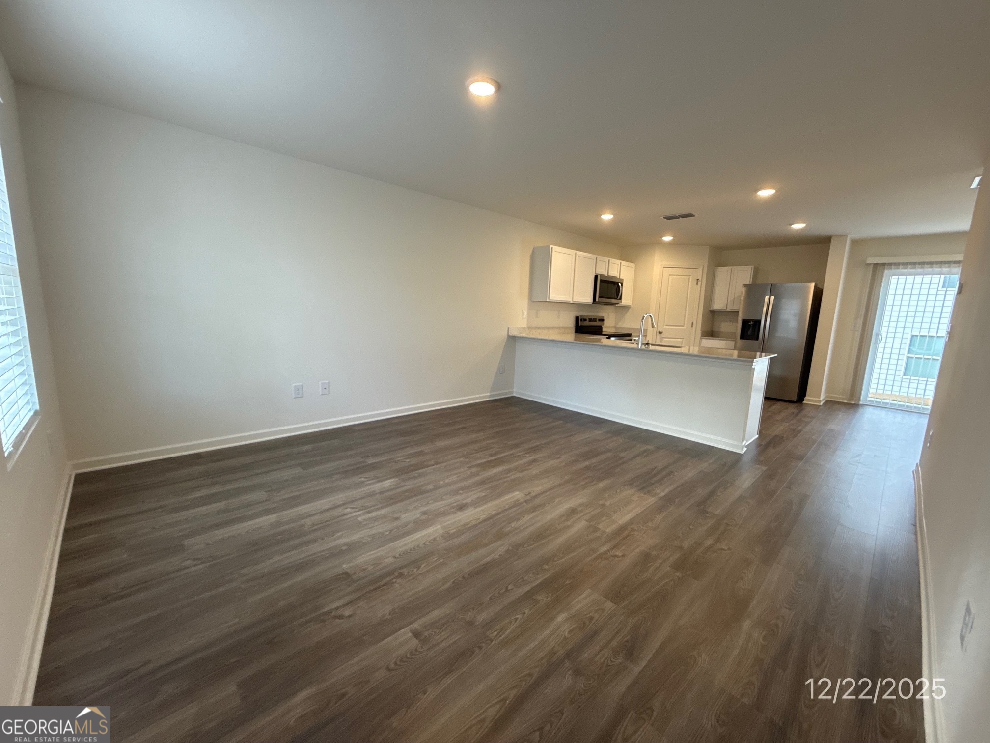 489 Grand Magnolia Street Jackson, GA 30233 - Photo 2 of 19 an empty room with wooden floor kitchen view and a window