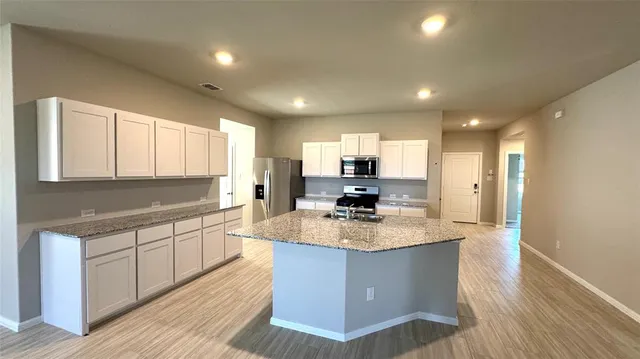 a large kitchen with stainless steel appliances granite countertop a sink dishwasher a stove and a refrigerator with wooden floor