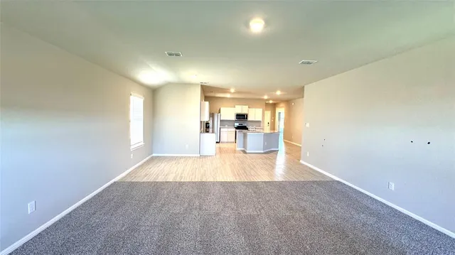 a view of a big room with wooden floor and a kitchen