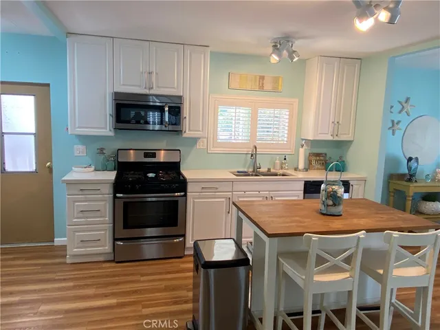 a kitchen with stainless steel appliances granite countertop a stove top oven a sink a dining table and chairs