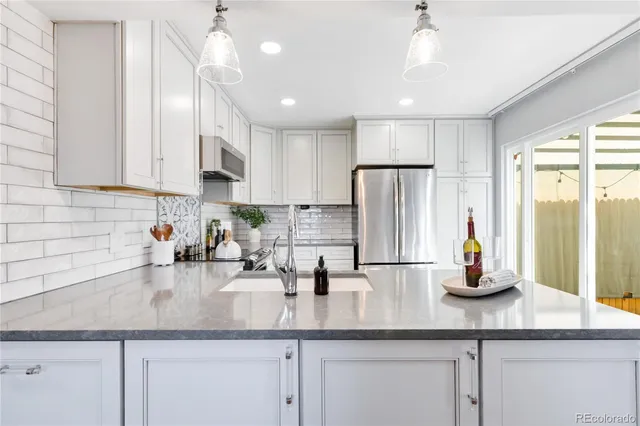 a kitchen with granite countertop a sink stainless steel appliances and white cabinets