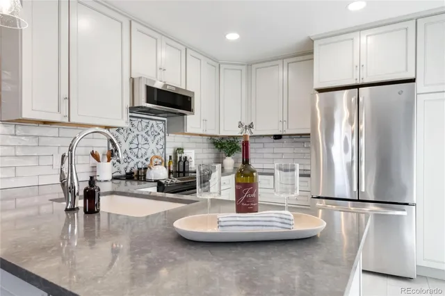 a kitchen with stainless steel appliances granite countertop a refrigerator a stove and a sink with wooden floor