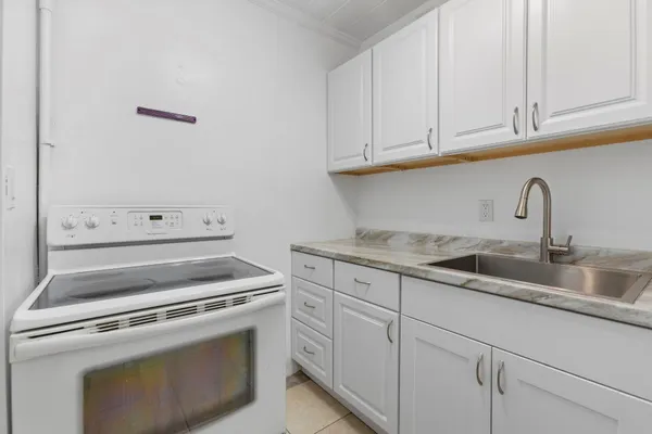 a kitchen with granite countertop white cabinets and a stove