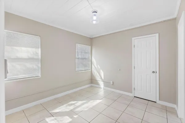 a view of an empty room with window and chandelier fan